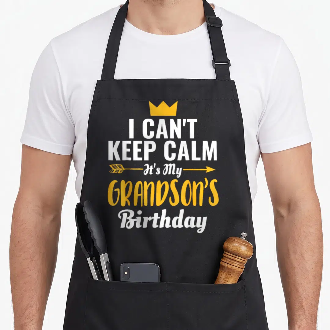 Grandson birthday apron - I Can't Keep Calm It's My Grandson's Birthday text with yellow crown and arrows on black — shown on a black cotton canvas apron against a white background