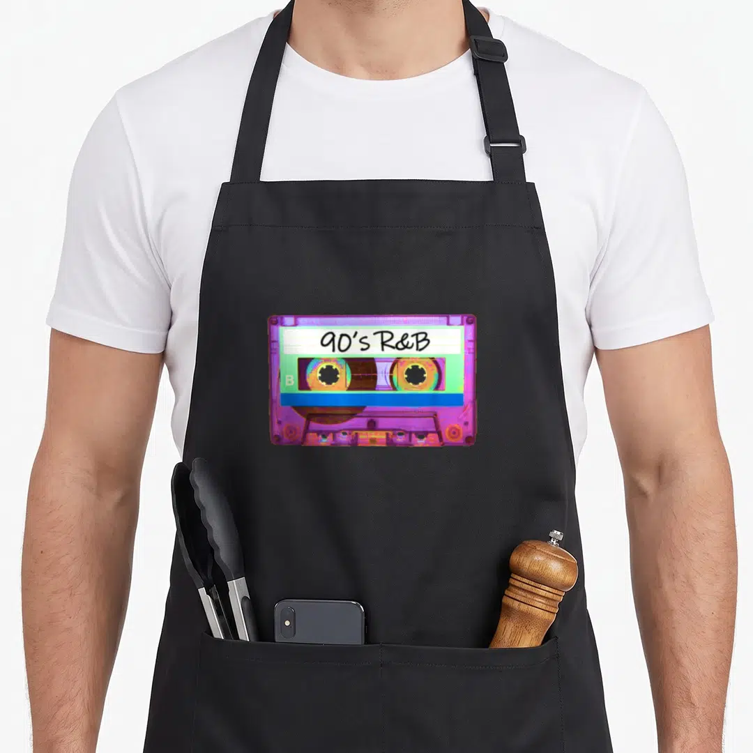 90s r aprons - Purple and blue cassette tape with 90's R&B text and letter B on white label — shown on a black cotton canvas apron against a white background