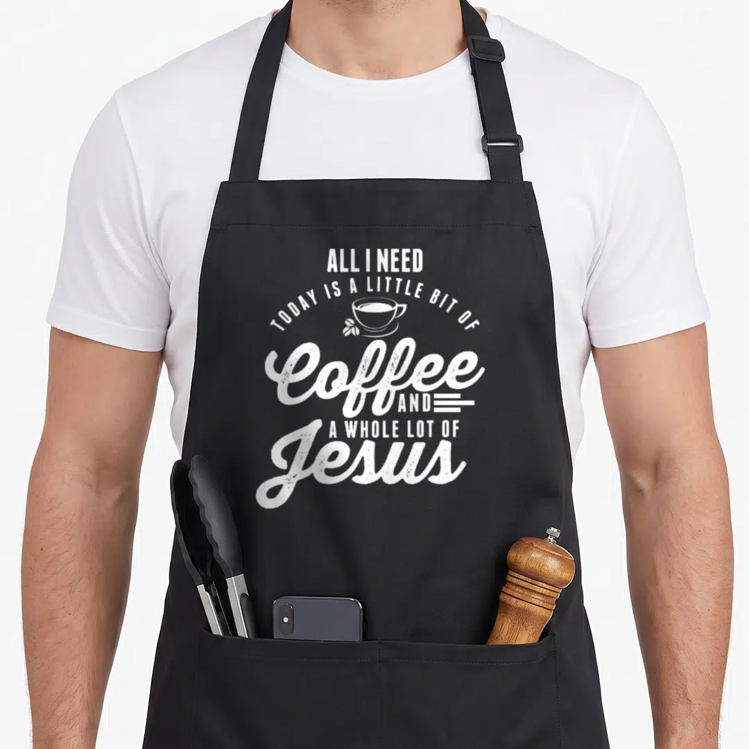 Funny jesus coffee apron - Stacked white text reading All I Need Today Is A Little Bit Of Coffee And A Whole Lot — shown on a black cotton canvas apron against a white background