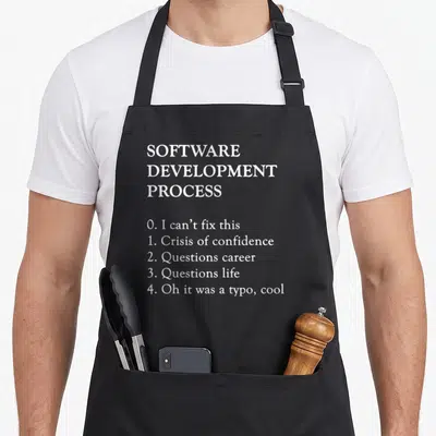 Software programming apron - White text listing software development process steps from crisis to typo realization — shown on a black cotton canvas apron against a white background