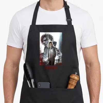 Requiem grace apron - Woman in brown jacket and man face in rain with red BIOHAZARD requiem text below — shown on a black cotton canvas apron against a white background