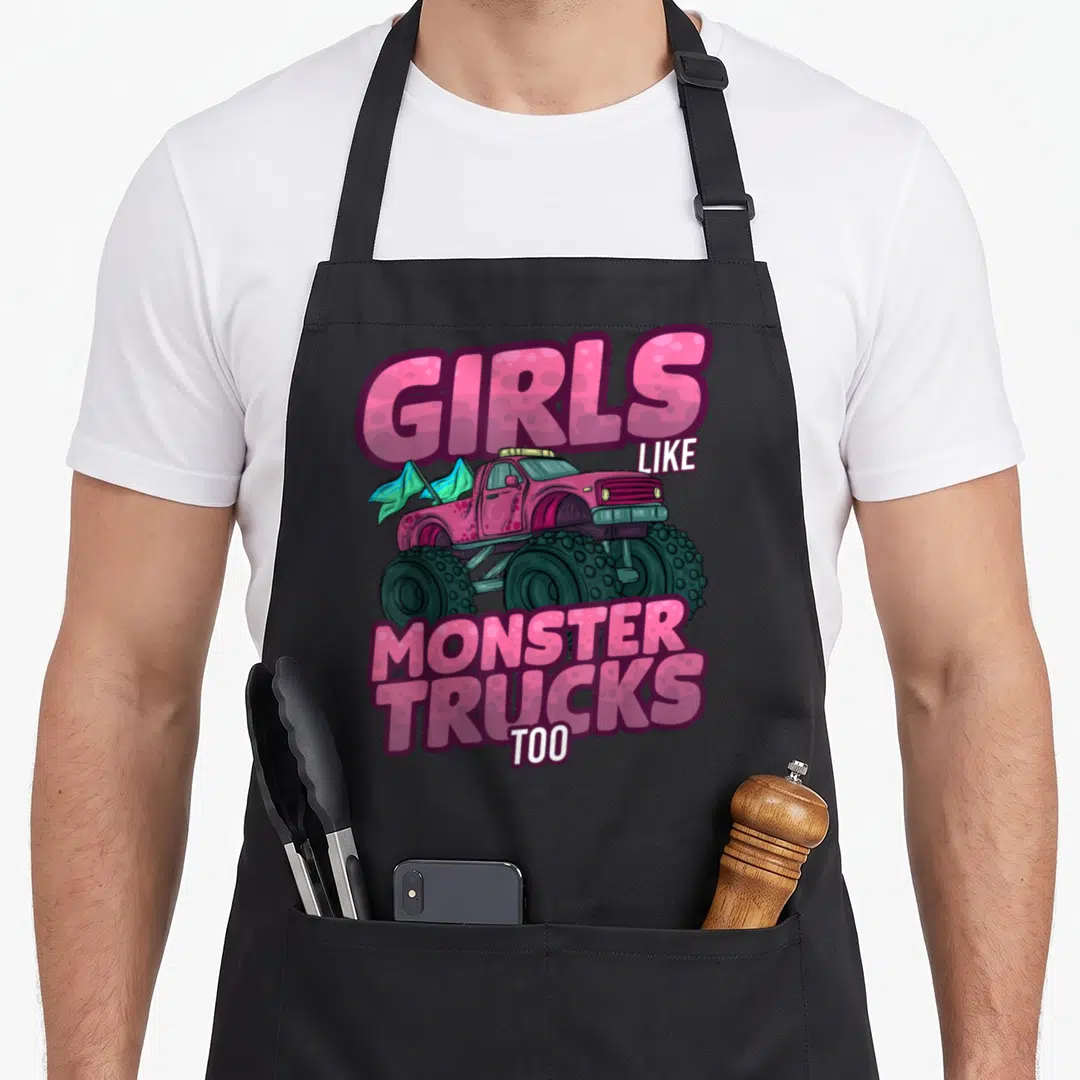 Monster mother truck apron - Pink monster truck with teal flags and GIRLS LIKE MONSTER TRUCKS TOO text — shown on a black cotton canvas apron against a white background