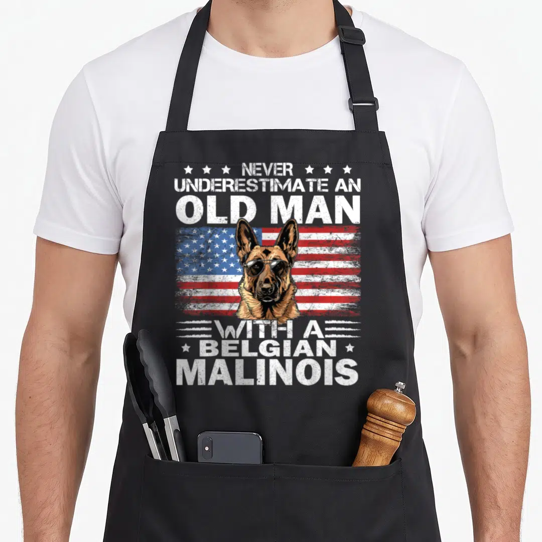 Malinois dog breed aprons - Belgian Malinois head with sunglasses over distressed USA flag and stacked white text — shown on a black cotton canvas apron against a white background