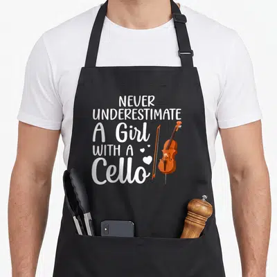 Youth cello apron - White text NEVER UNDERESTIMATE A Girl WITH A Cello beside brown cello and hearts on black apron — shown on a black cotton canvas apron against a white background