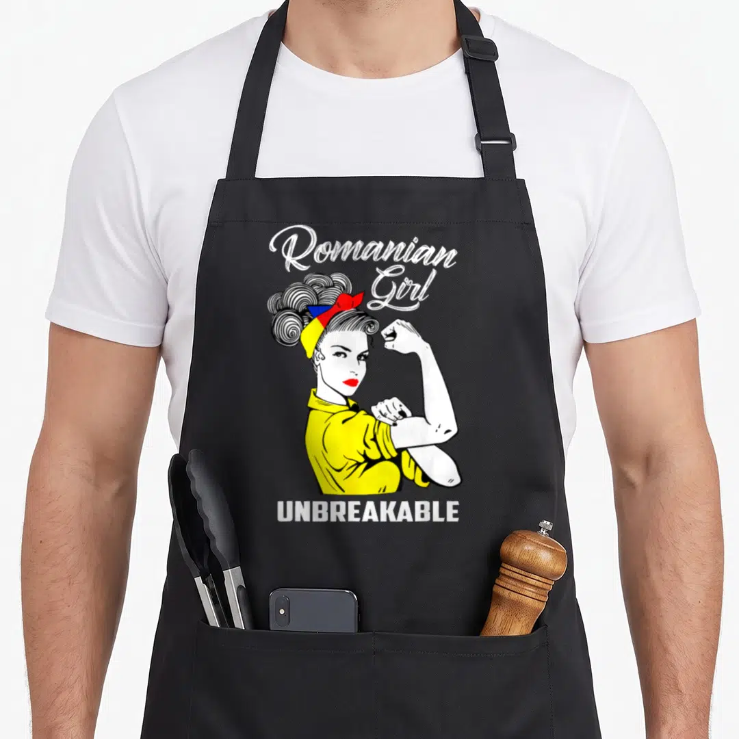 Unbreakable romanian apron - Cartoon woman flexing arm with Romanian flag headband and text Romanian Girl UNBREAKABLE — shown on a black cotton canvas apron against a white background
