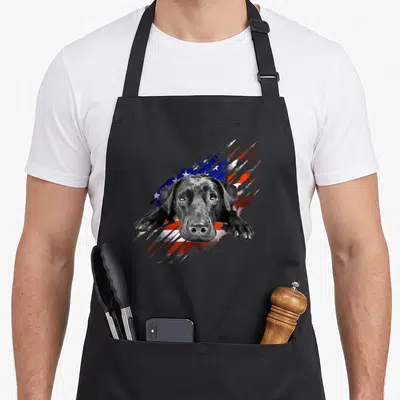 Labrador bird aprons - Black lab dog head and paws over distressed USA flag stripes — shown on a black cotton canvas apron against a white background
