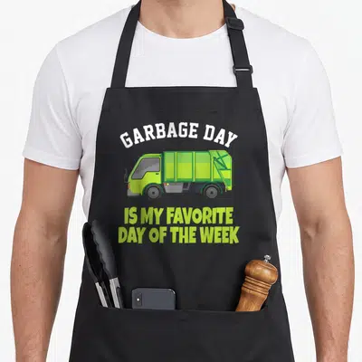 Disposal truck apron - Cartoon lime green garbage truck with white and lime green text reading GARBAGE DAY IS MY — shown on a black cotton canvas apron against a white background