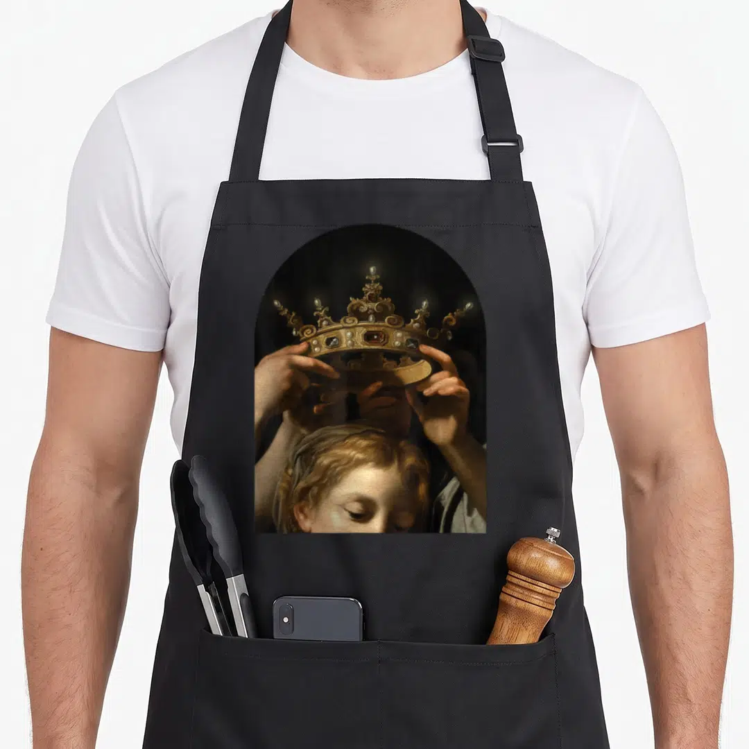 Cavarozzi renaissance apron - Golden crown held by two hands above a face in gold black and brown tones — shown on a black cotton canvas apron against a white background