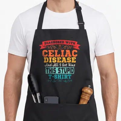 Vintage disease celiac awareness apron - Red ribbon and stacked text reading Diagnosed With Celiac Disease And All I — shown on a black cotton canvas apron against a white background