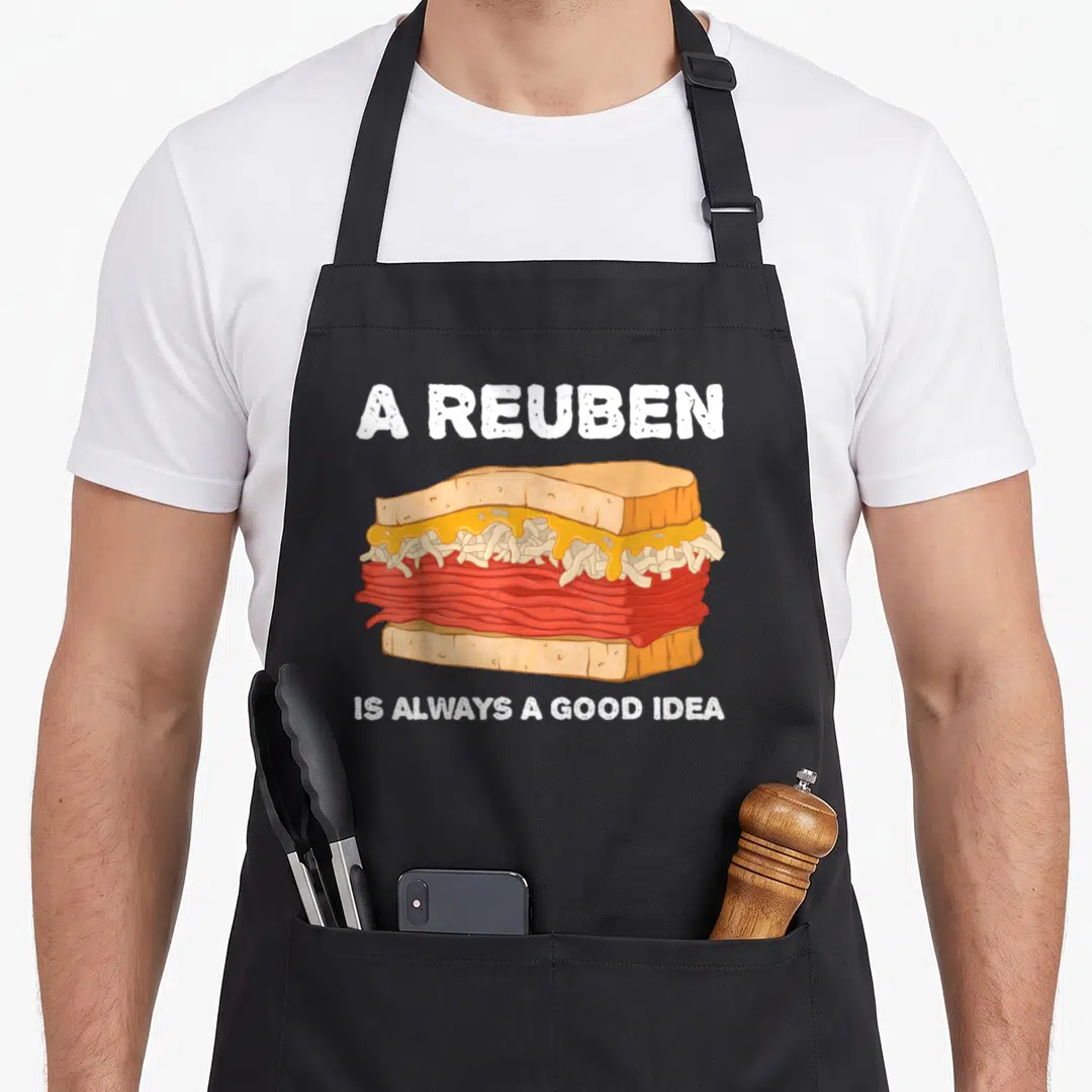 Alway reuben apron - Cartoon reuben sandwich with white text reading A REUBEN IS ALWAYS A GOOD IDEA — shown on a black cotton canvas apron against a white background