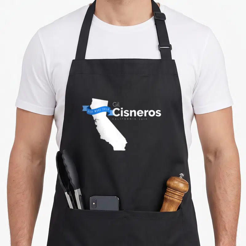 Gil midterms apron - White California map with blue ribbon reading BLUE WAVE 2018 and Gil Cisneros text — shown on a black cotton canvas apron against a white background