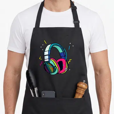 Headphone sound of music apron - Cartoon headphones in pink teal blue and yellow with geometric shapes — shown on a black cotton canvas apron against a white background