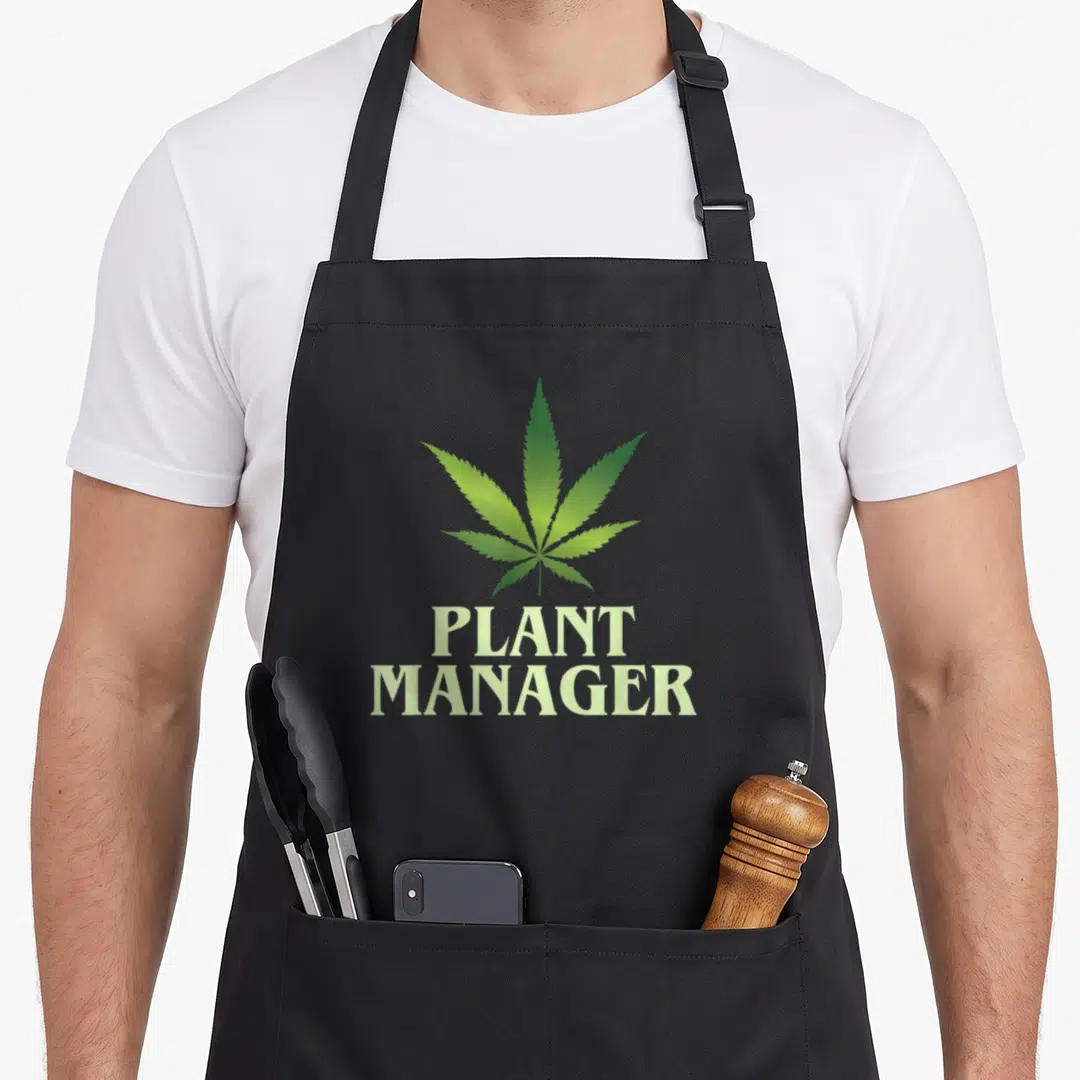 Cannabis plant apron - Green cannabis leaf above stacked PLANT MANAGER text in minimalist style — shown on a black cotton canvas apron against a white background