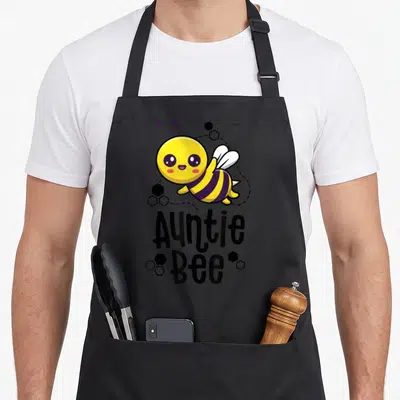 Aunt bee apron - Cartoon bee with yellow purple stripes and Auntie Bee text surrounded by black hexagons — shown on a black cotton canvas apron against a white background