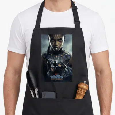 Poster panther apron - Photo of woman in black blue and gold armor with Marvel Studios Black Panther text overlay — shown on a black cotton canvas apron against a white background