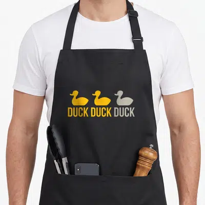 Vintage duck minnesota apron - Three ducks in yellow and grey above DUCK DUCK DUCK text — shown on a black cotton canvas apron against a white background