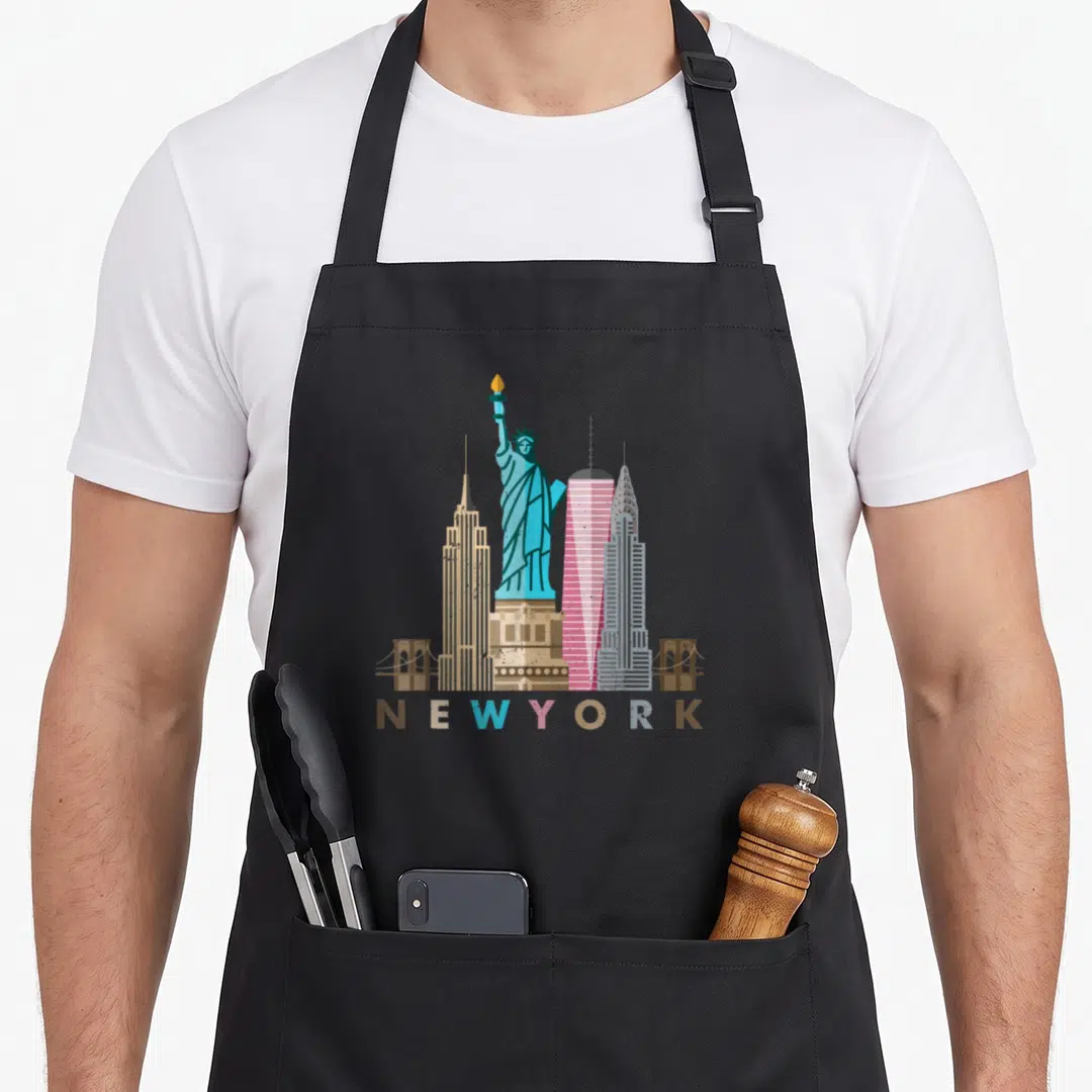 Liberty new york apron - Minimalist NYC skyline with Statue of Liberty and multi-colored NEW YORK text — shown on a black cotton canvas apron against a white background