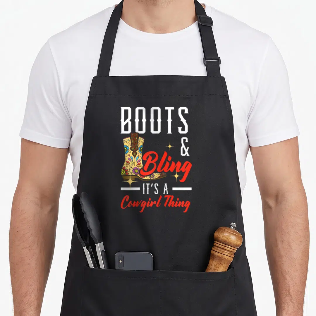 Bling western apron - Decorated cowboy boot with BOOTS & Bling It's A Cowgirl Thing text — shown on a black cotton canvas apron against a white background
