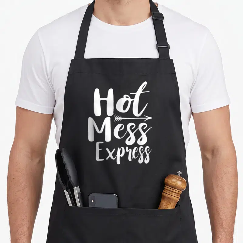Hot mess apron - White stacked text Hot Mess Express with right-pointing arrow between lines — shown on a black cotton canvas apron against a white background