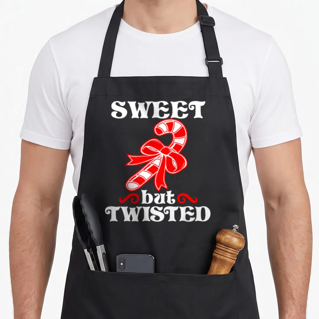 Sweet candy cane apron - SWEET but TWISTED text with red and white striped candy cane and bow — shown on a black cotton canvas apron against a white background