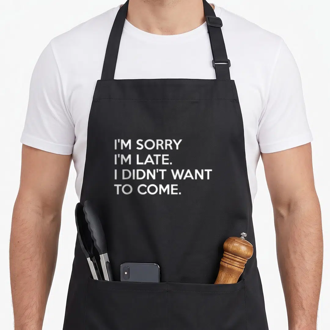 Sorry late apron - White stacked text reading I'M SORRY I'M LATE on black fabric — shown on a black cotton canvas apron against a white background