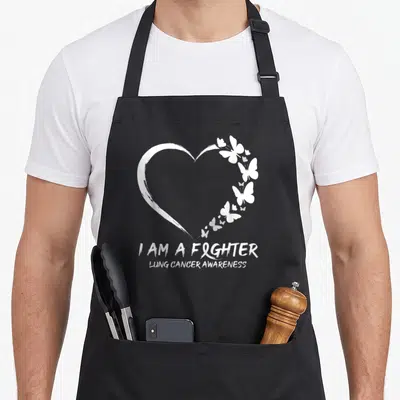 Fighter lung butterfly apron - White heart made of brushstroke and butterflies with I AM A FIGHTER text and ribbon — shown on a black cotton canvas apron against a white background