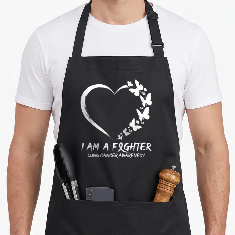 Fighter lung butterfly apron - White heart made of brushstroke and butterflies with I AM A FIGHTER text and ribbon — shown on a black cotton canvas apron against a white background