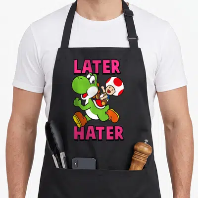 Later toad apron - Pink LATER HATER text above and below running green Yoshi carrying Toad — shown on a black cotton canvas apron against a white background