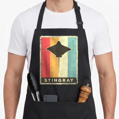 Stingray animal apron - Retro black stingray silhouette on red orange yellow and teal vertical stripes with text — shown on a black cotton canvas apron against a white background