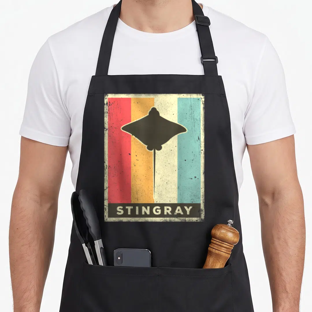 Stingray animal apron - Retro black stingray silhouette on red orange yellow and teal vertical stripes with text — shown on a black cotton canvas apron against a white background
