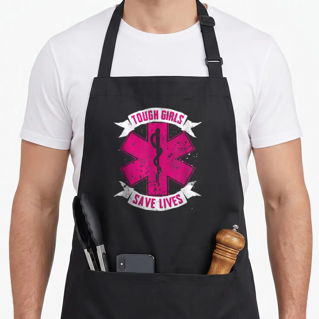 Tough emt apron - Pink Star of Life with Rod of Asclepius and white ribbons reading TOUGH GIRLS SAVE LIVES — shown on a black cotton canvas apron against a white background