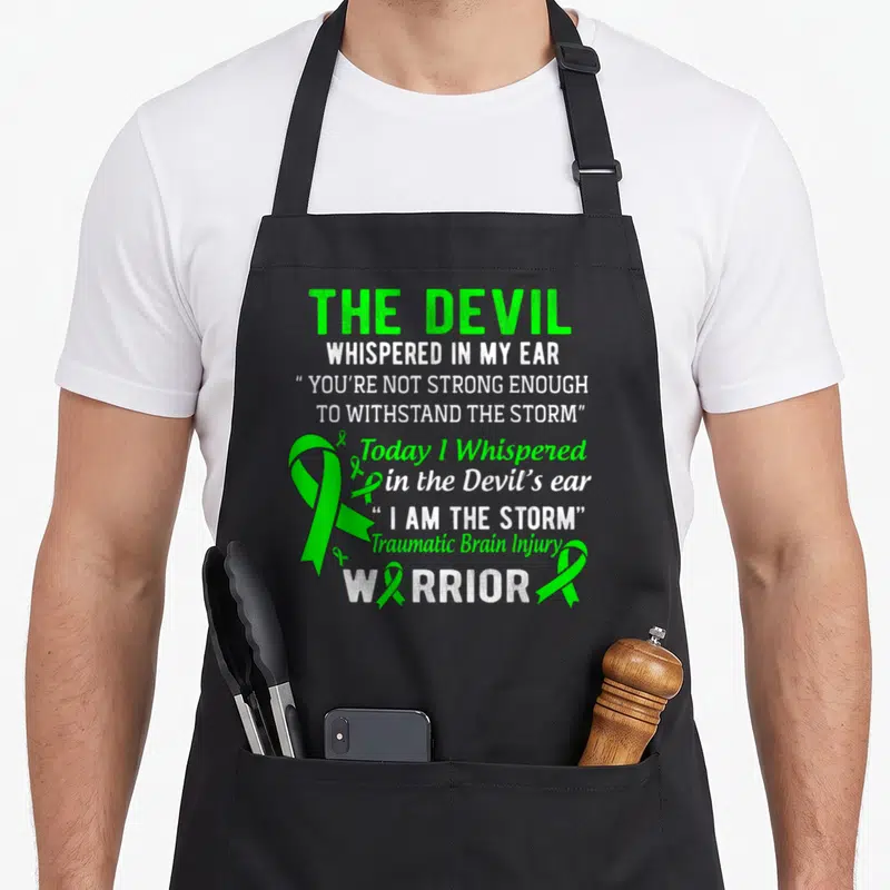 Storm tbi awareness apron - Green and white stacked text with one large and four small TBI awareness ribbons — shown on a black cotton canvas apron against a white background
