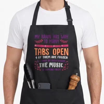 Many open apron - Stacked text about frozen tabs and music with pink banner and musical notes — shown on a black cotton canvas apron against a white background
