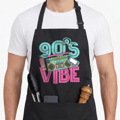 Music costume 90s apron - Teal boombox, pink phone, MP3 player, and 90'S VIBE text in cartoon style — shown on a black cotton canvas apron against a white background
