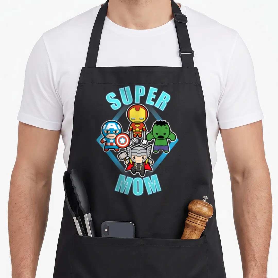 Comic mother's day aprons - SUPER MOM text arching over four chibi superheroes on a blue diamond — shown on a black cotton canvas apron against a white background