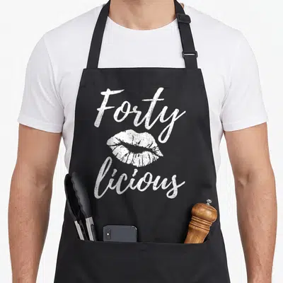 Fortylicious 40th apron - White distressed lips with Forty above and licious below text — shown on a black cotton canvas apron against a white background