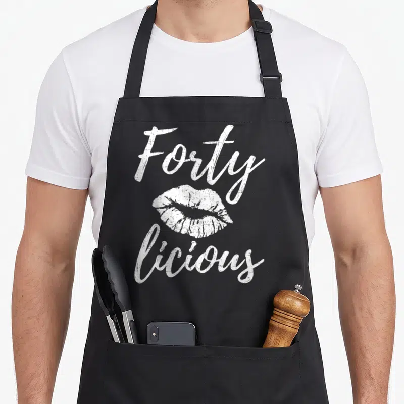 Fortylicious 40th apron - White distressed lips with Forty above and licious below text — shown on a black cotton canvas apron against a white background