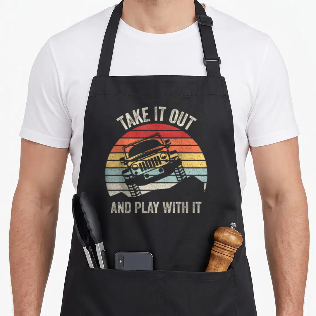 Catch fried apron - Distressed off-road vehicle on striped red orange yellow blue sun with arched text — shown on a black cotton canvas apron against a white background