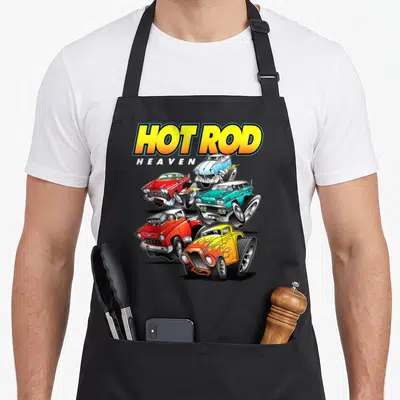 Hot antique apron - HOT ROD HEAVEN text above five overlapping cartoon hot rods in yellow red blue and teal — shown on a black cotton canvas apron against a white background