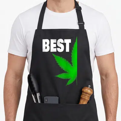 Bff couple apron - White BEST text overlapping a large green cannabis leaf illustration — shown on a black cotton canvas apron against a white background