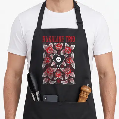 Alkaline rose apron - Distressed red ALKALINE TRIO text above red roses and white heart with skull — shown on a black cotton canvas apron against a white background