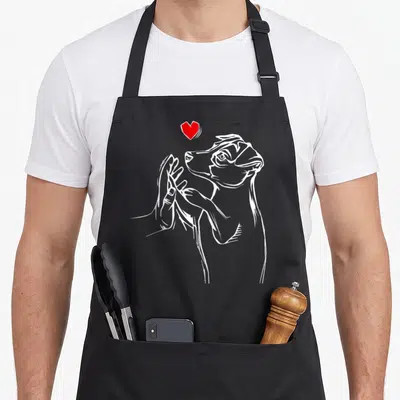 Russell dog dad apron - White line-art terrier being petted by a hand with a red heart floating above — shown on a black cotton canvas apron against a white background