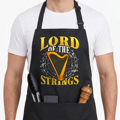 Harp key lover apron - Golden harp illustration surrounded by white music notes and arched text LORD OF THE STRINGS — shown on a black cotton canvas apron against a white background