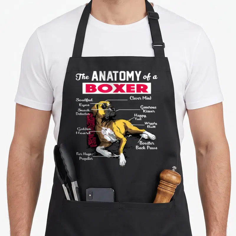 Anatomy boxer dog apron - Cartoon boxer diagram with labels like snack detector and wiggly butt connected by white lines — shown on a black cotton canvas apron against a white background