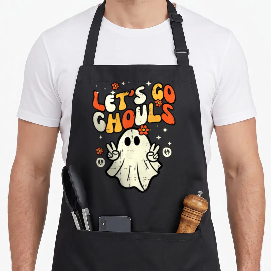 Ghoul halloween apron - Retro ghost making peace signs under stacked orange and white text reading LET'S GO GHOULS — shown on a black cotton canvas apron against a white background