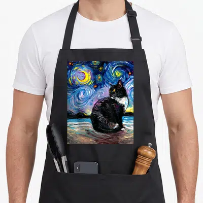 Beach tuxedo apron - Black cat sitting in swirling blue and yellow starry night watercolor painting on black fabric — shown on a black cotton canvas apron against a white background