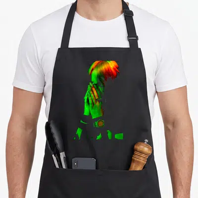 Eilish face apron - Fragmented photo of a person in green orange and red with a watch below hands — shown on a black cotton canvas apron against a white background