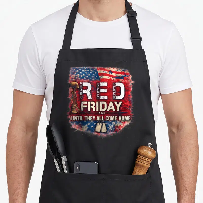Friday patriotic apron - Red Friday military memorial with helmet rifle dog tags on distressed flag background — shown on a black cotton canvas apron against a white background