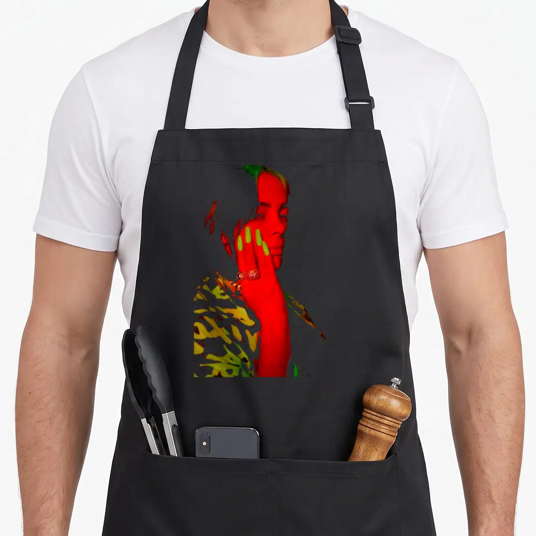 Billie eilish novelty apron - Stylized red photo of person face and hand with lime green nails and yellow accents — shown on a black cotton canvas apron against a white background