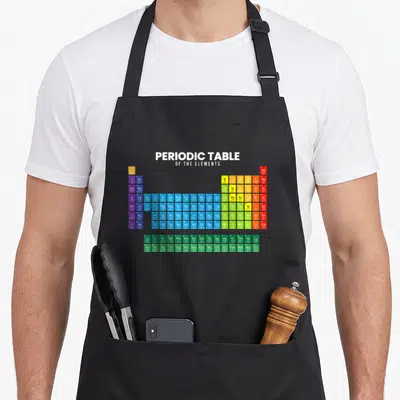 Cool periodic table apron - Periodic Table of Elements chart with white, blue, green, yellow, red, and purple tiles — shown on a black cotton canvas apron against a white background
